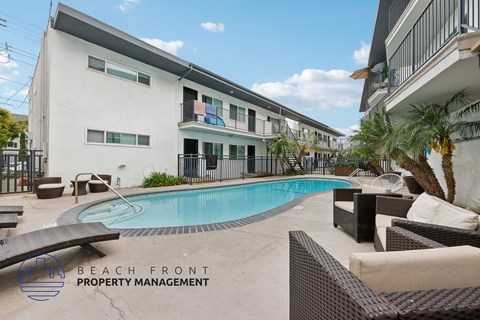 A pool area with lounge chairs and a building in the background.