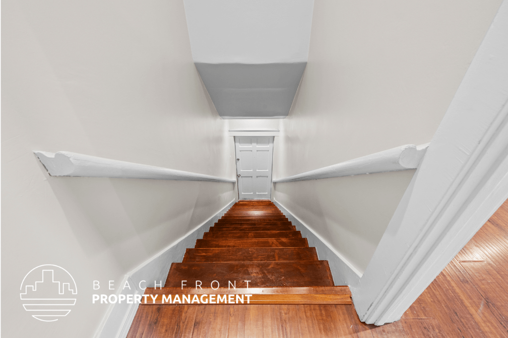 a view down the stairs of a house with white walls and wood floors