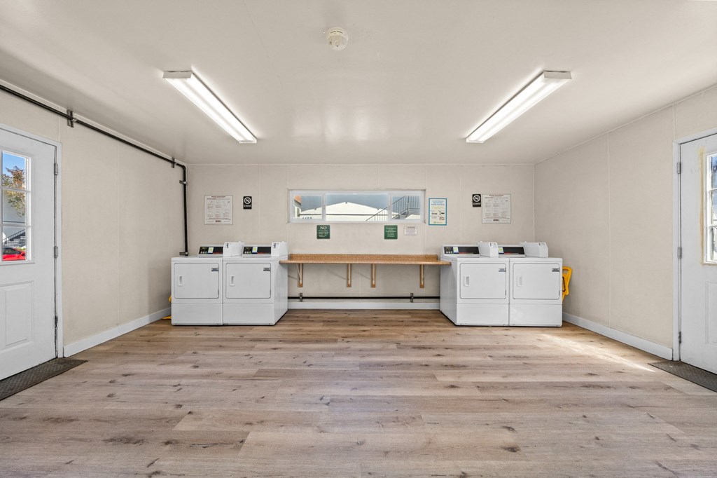 a room with white washing machines and a wooden floor