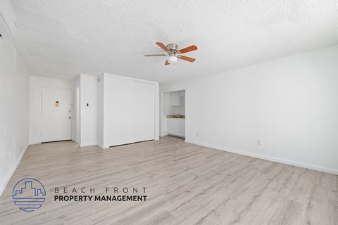 A spacious room with a ceiling fan and wooden flooring.