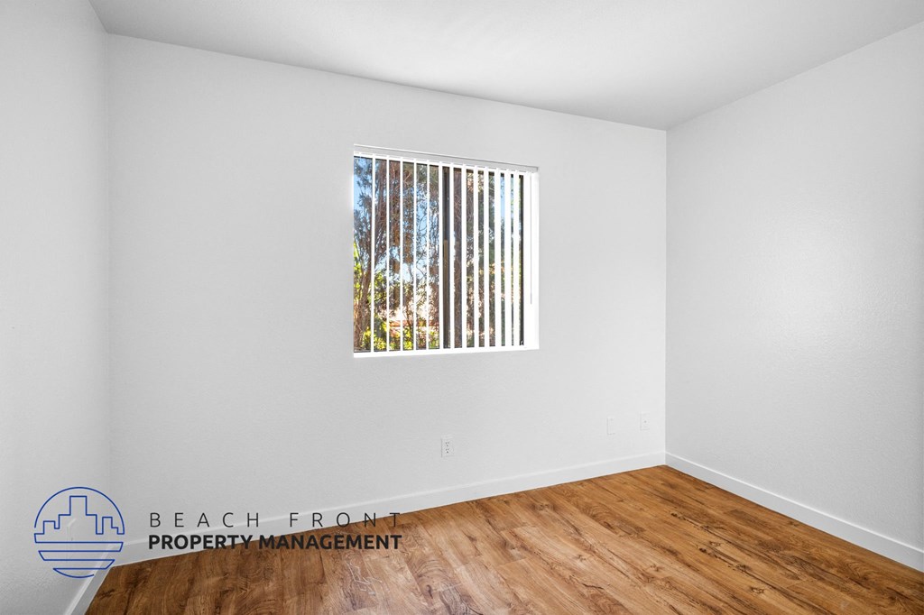 the living room of the new home with wood flooring and a window
