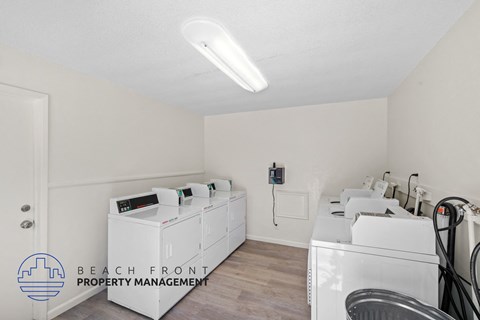 a laundry room with white washers and dryers and a row of washing machines