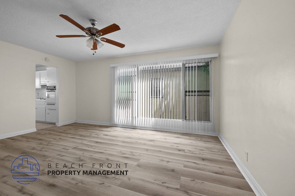 an empty living room with a ceiling fan and a window