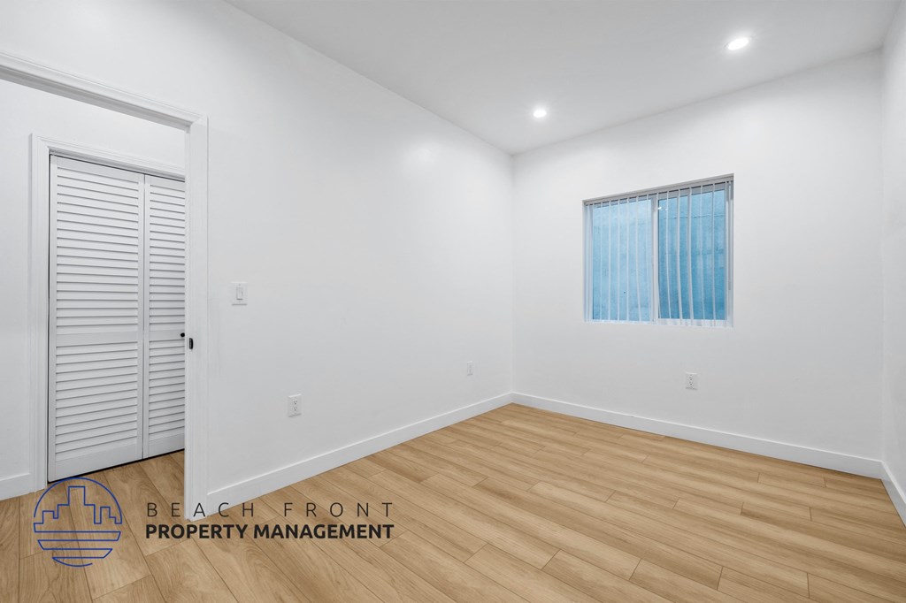 a living room with white walls and wood flooring and a window