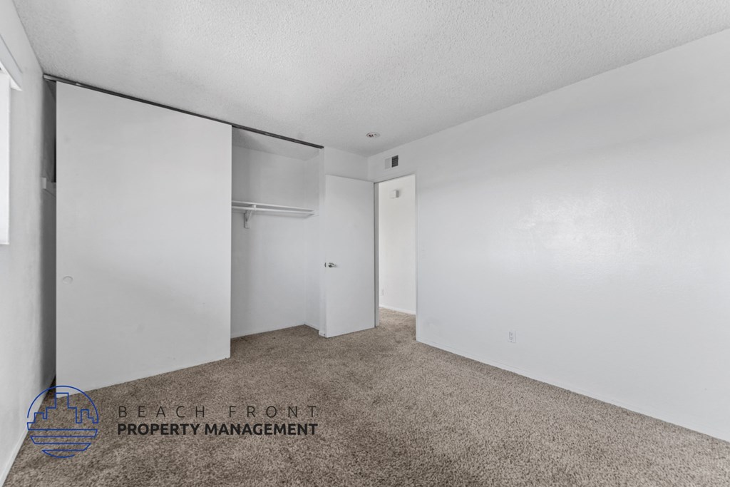 A carpeted room with a sliding door and a wall-mounted air conditioning unit.