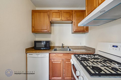 A kitchen with a white stove top oven and a white dishwasher.