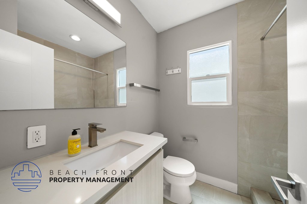 A bathroom with a toilet, sink, and mirror.