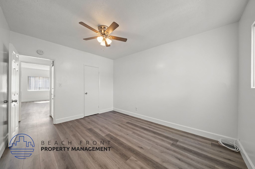 A room with a ceiling fan and wooden flooring.