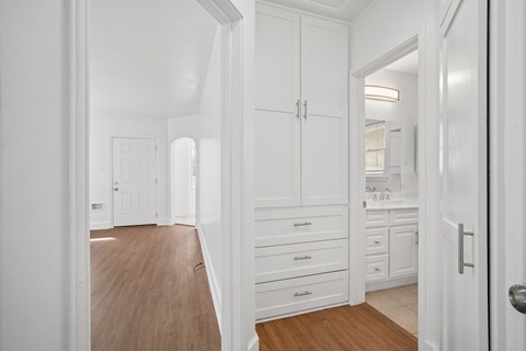 A white kitchen with wooden floors and white cabinets.