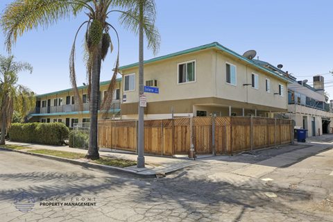 A building with a blue sign on the front is surrounded by a wooden fence.