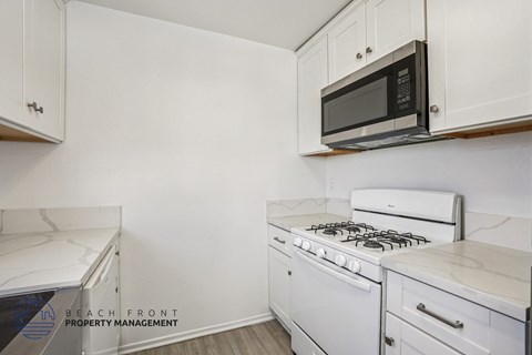 A white kitchen with a black microwave above the stove.