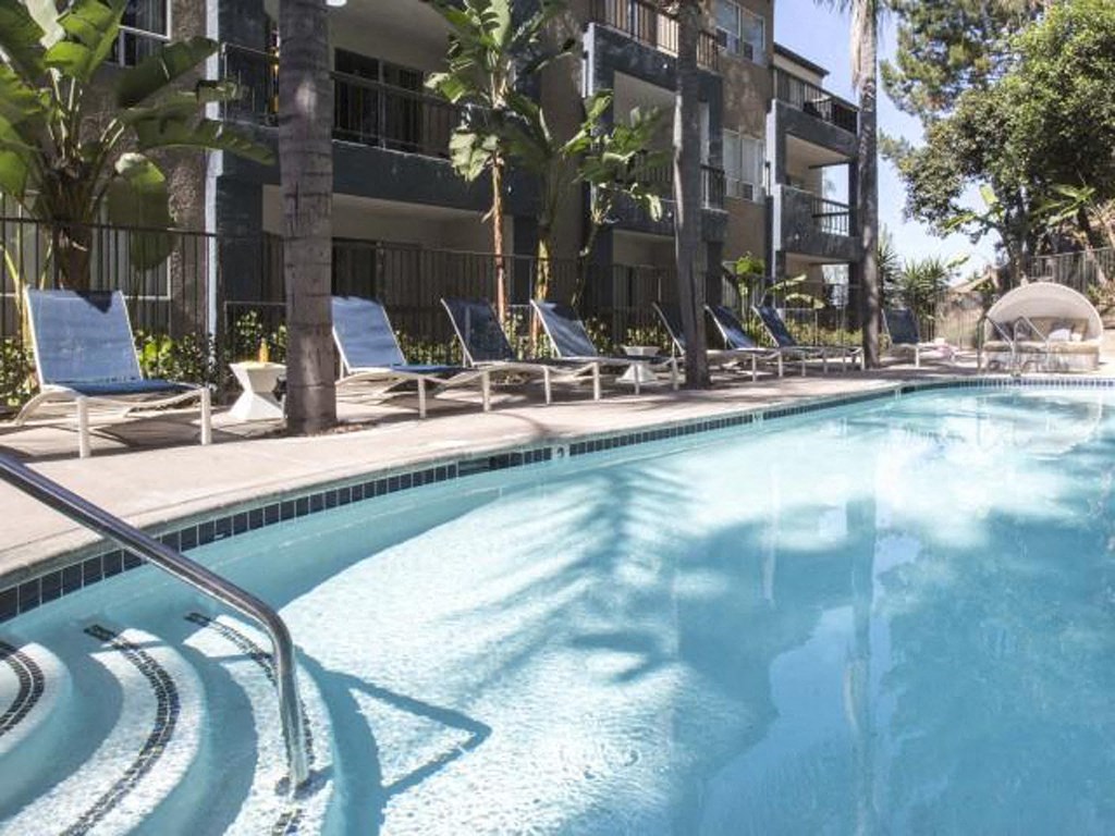 a swimming pool with chairs and a building in the background