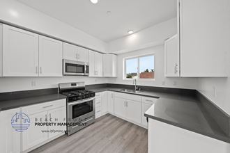 a white kitchen with black counter tops and white cabinets