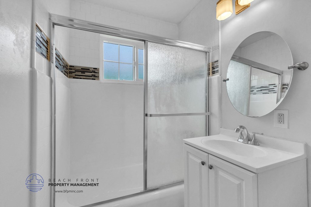 a bathroom with a white sink and a shower with a glass door