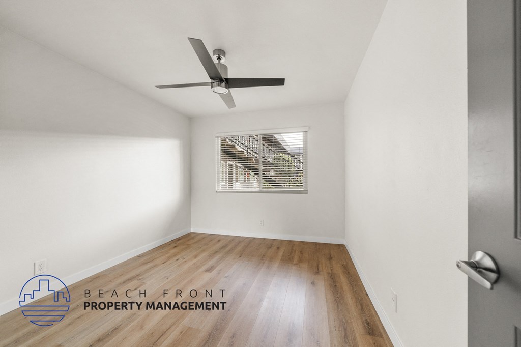 A room with a ceiling fan and wooden flooring.