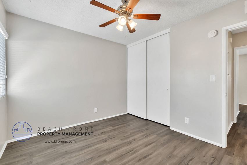 the spacious living room with two closets and a ceiling fan