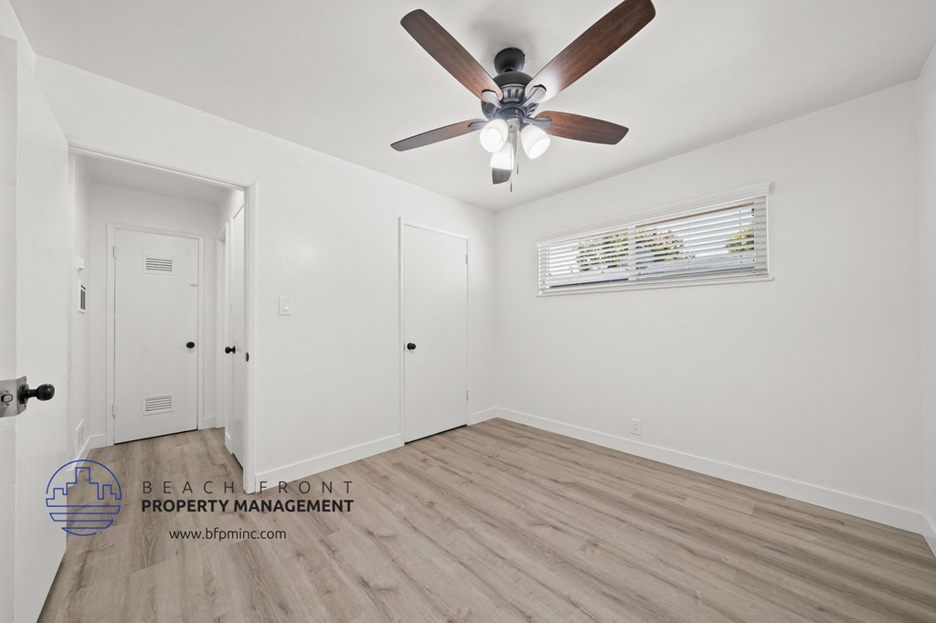a bedroom with hardwood floors and a ceiling fan