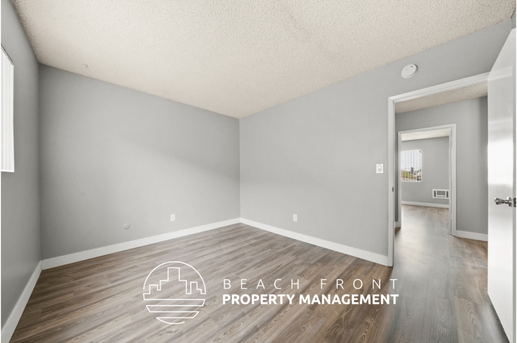 a white and grey room with wood flooring and a door to a hallway