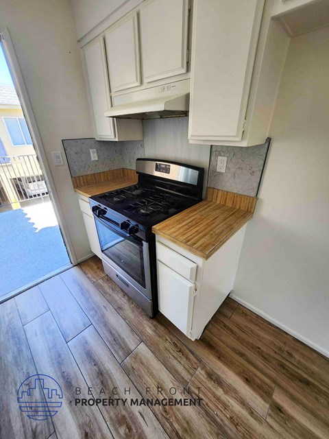 A kitchen with a black stove top oven and white cabinets.