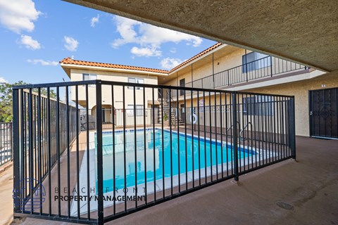 a swimming pool behind a wrought iron fence in front of a house