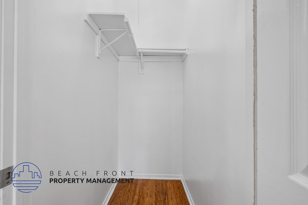 A white room with a wooden floor and a white shelf on the wall.