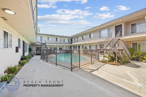 A pool area of a building with a sign that says "Beach Front Property Management".