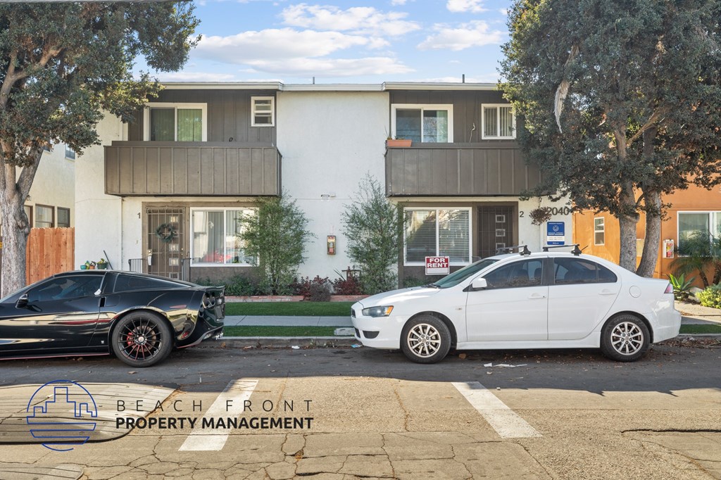 Two cars parked in front of a building with the logo Beach Front Property Management.