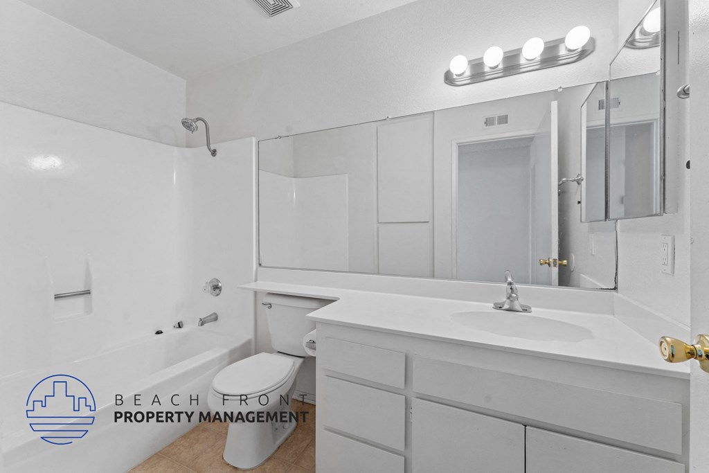 A bathroom with a white tub, sink, and mirror.