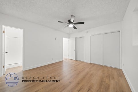 A spacious room with a ceiling fan and wooden flooring.