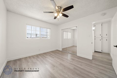 A spacious room with a ceiling fan and wooden flooring.