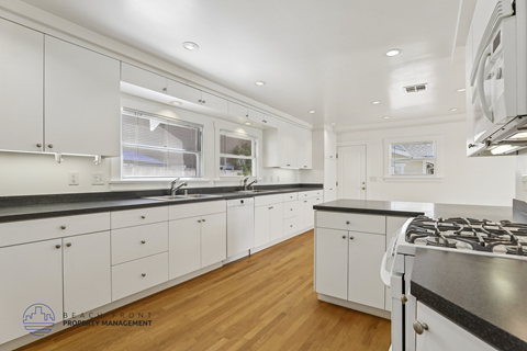 A modern kitchen with white cabinets and a black countertop.
