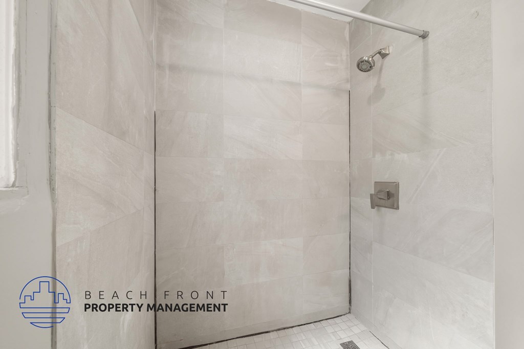 A shower area with a glass door and a shower head.