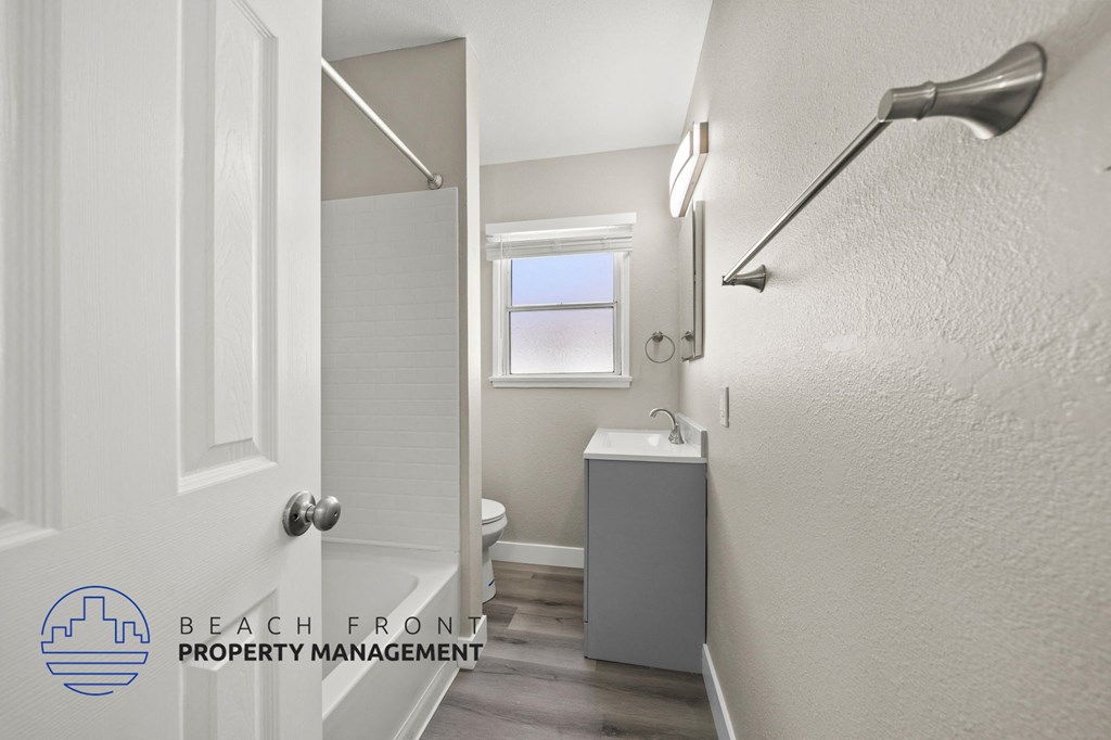 A bathroom with a toilet, sink, and a window.