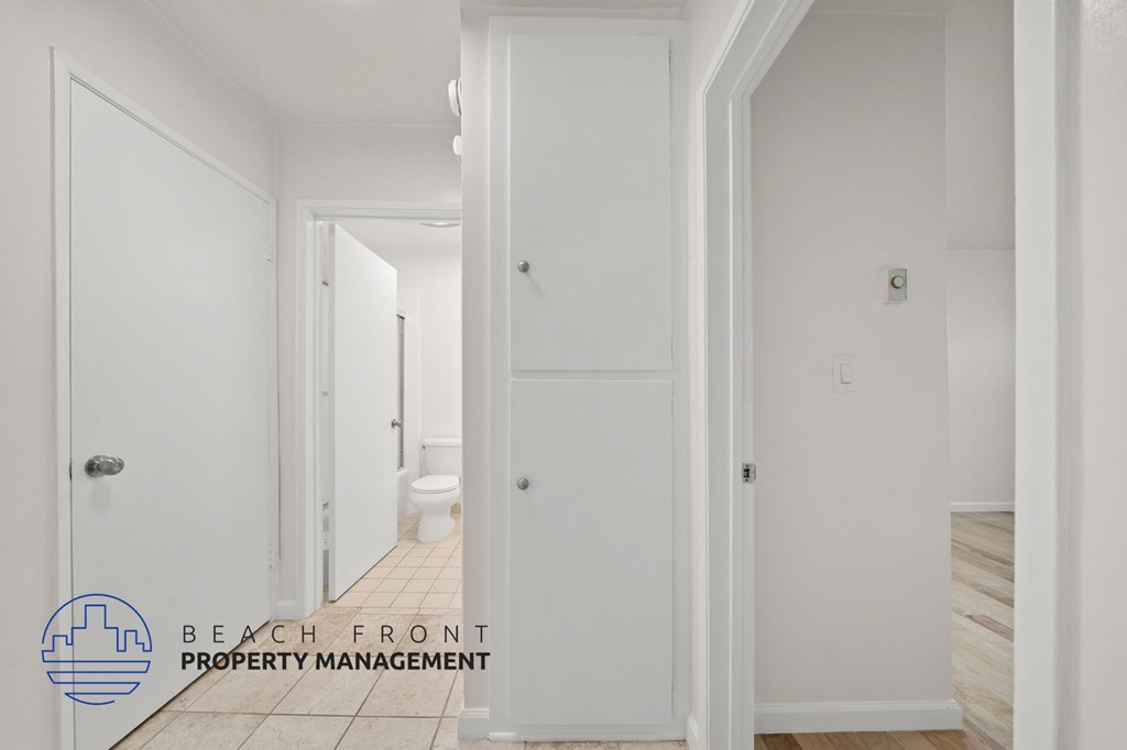 A hallway with white doors and a logo for Beach Front Property Management.
