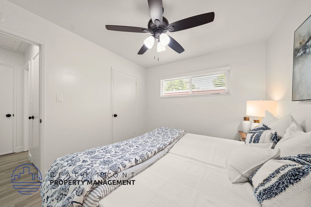 A bedroom with a bed, pillows, and a ceiling fan.