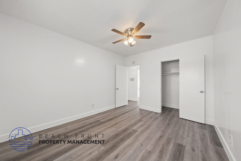 A spacious room with a ceiling fan and wooden flooring.