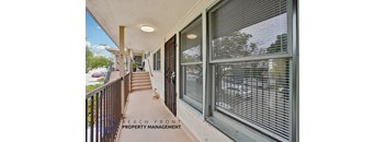 A balcony with a view of the beach and a sign for Beach Front Property Management.