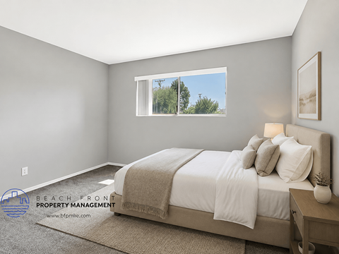 A well-lit bedroom with a large bed and a window showing a view of the outdoors.