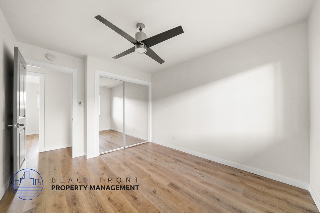 A room with a ceiling fan and wooden flooring.