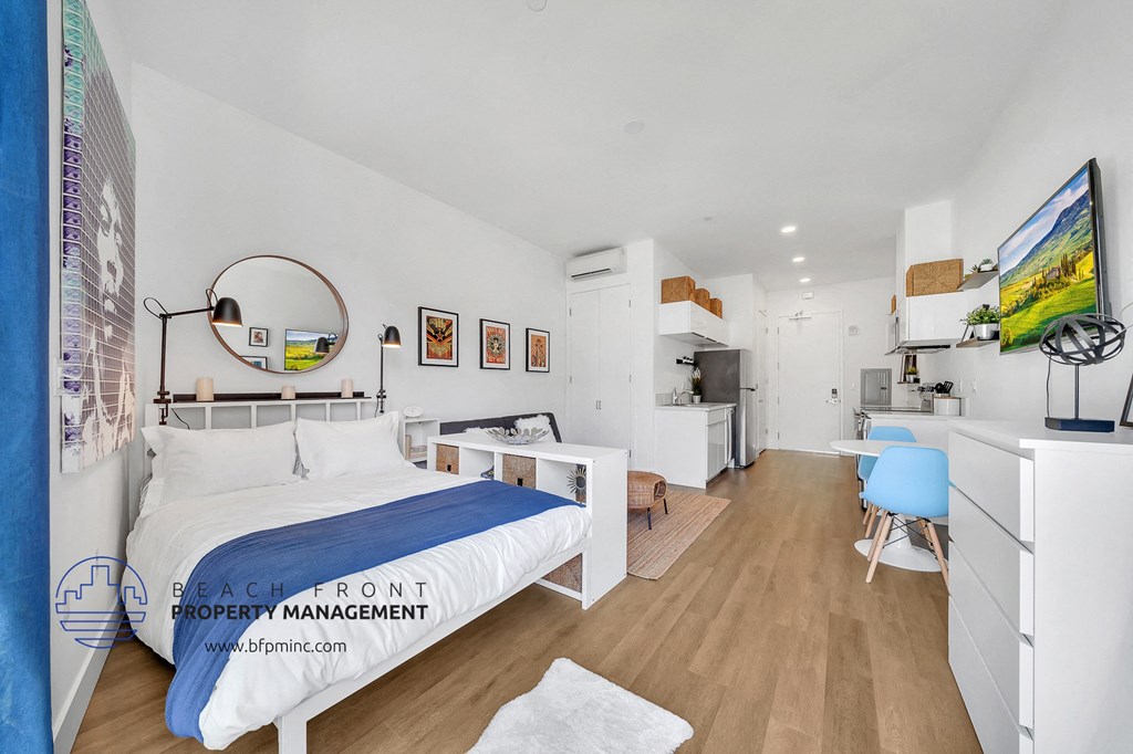 a bedroom with a bed and a desk and a kitchen