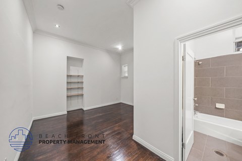 a bedroom with white walls and wood flooring and a walk in closet
