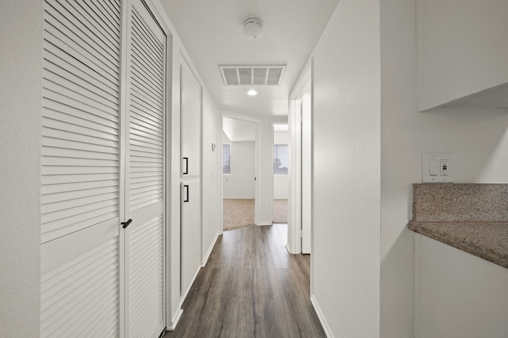 a long hallway with white doors and white walls and wood floors