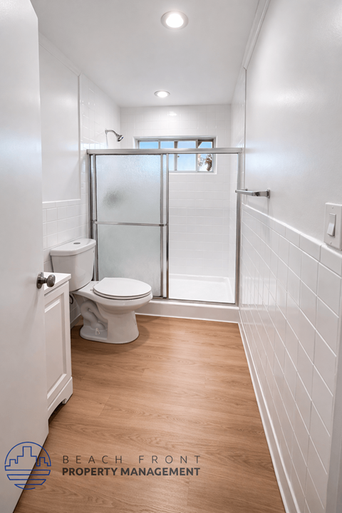 A white bathroom with a toilet, sink, and walk-in shower.