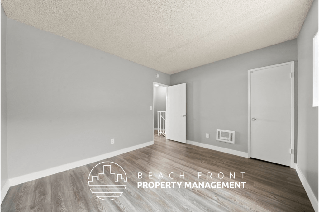 the spacious living room with hardwood flooring and a door to the hallway