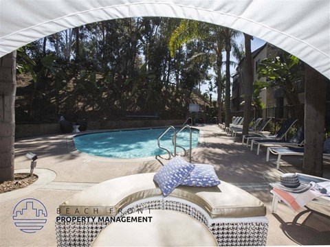 A pool area with a white canopy and a pool chair with a blue and white pillow on it.
