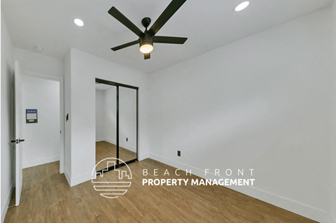 a living room with white walls and a ceiling fan