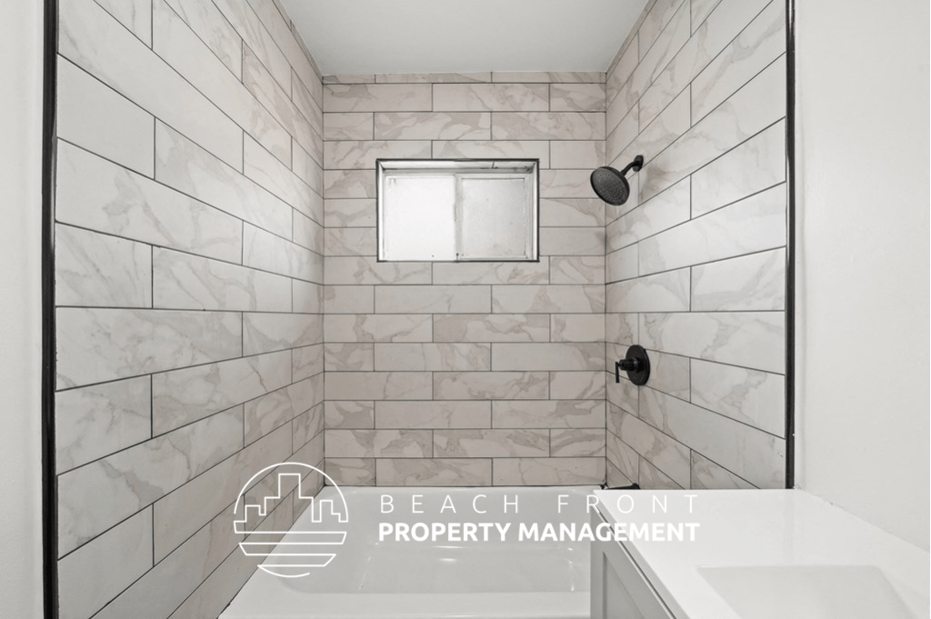 a white tiled bathroom with a shower and a sink