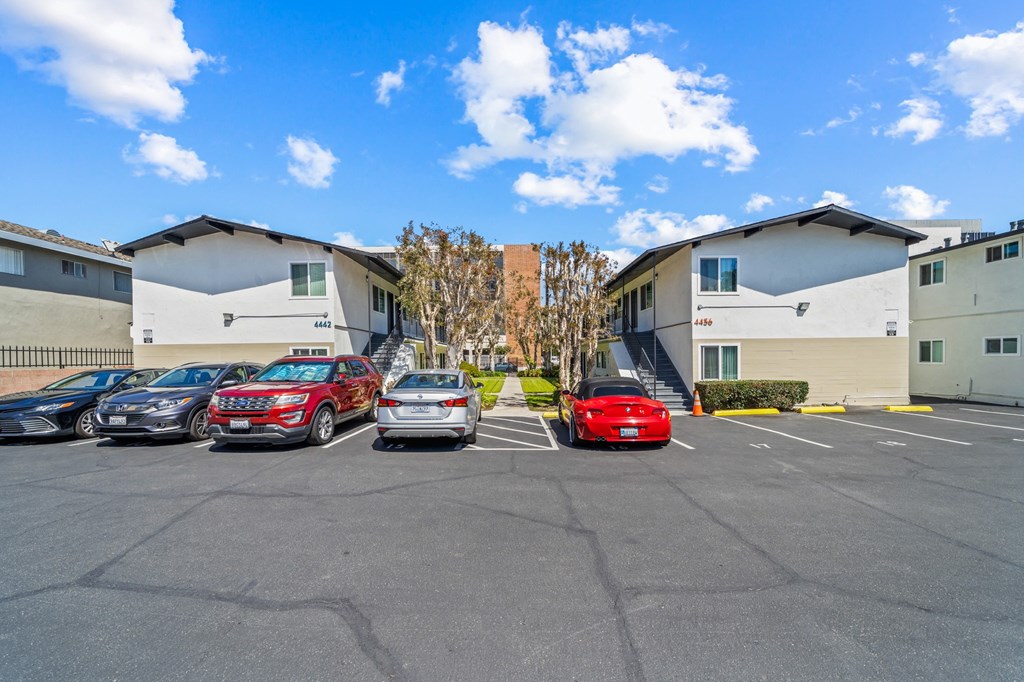 a parking lot with cars parked in front of apartment buildings