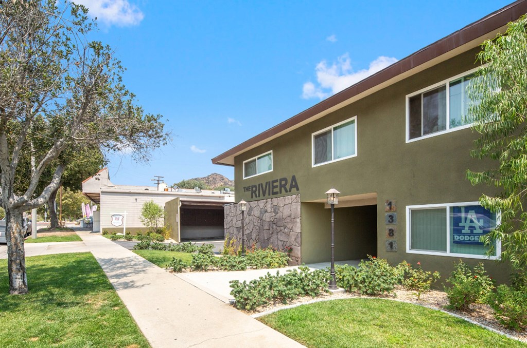 a building with a sidewalk and grass and trees in front of it