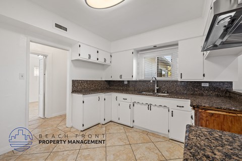 A kitchen with white cabinets and a granite countertop.